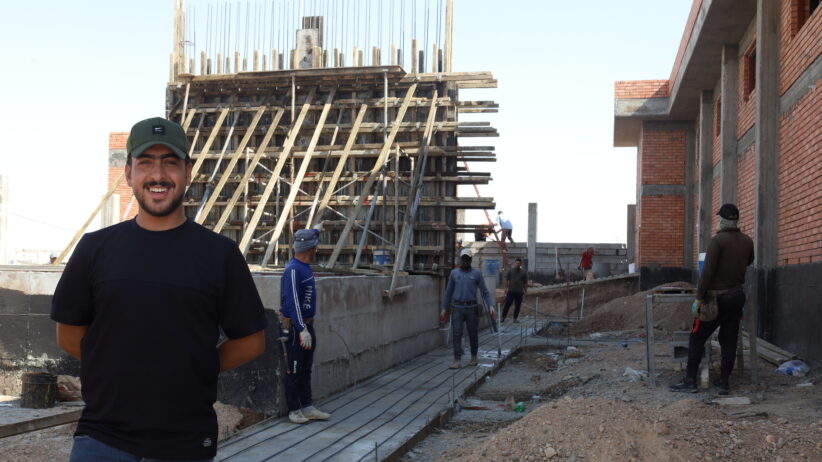 Mohammed stands with the governments new power station in the background